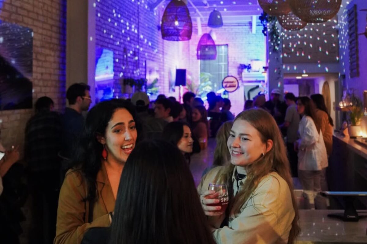 Guests mingling under woven pendant lamps at an evening event lit in purple and blue